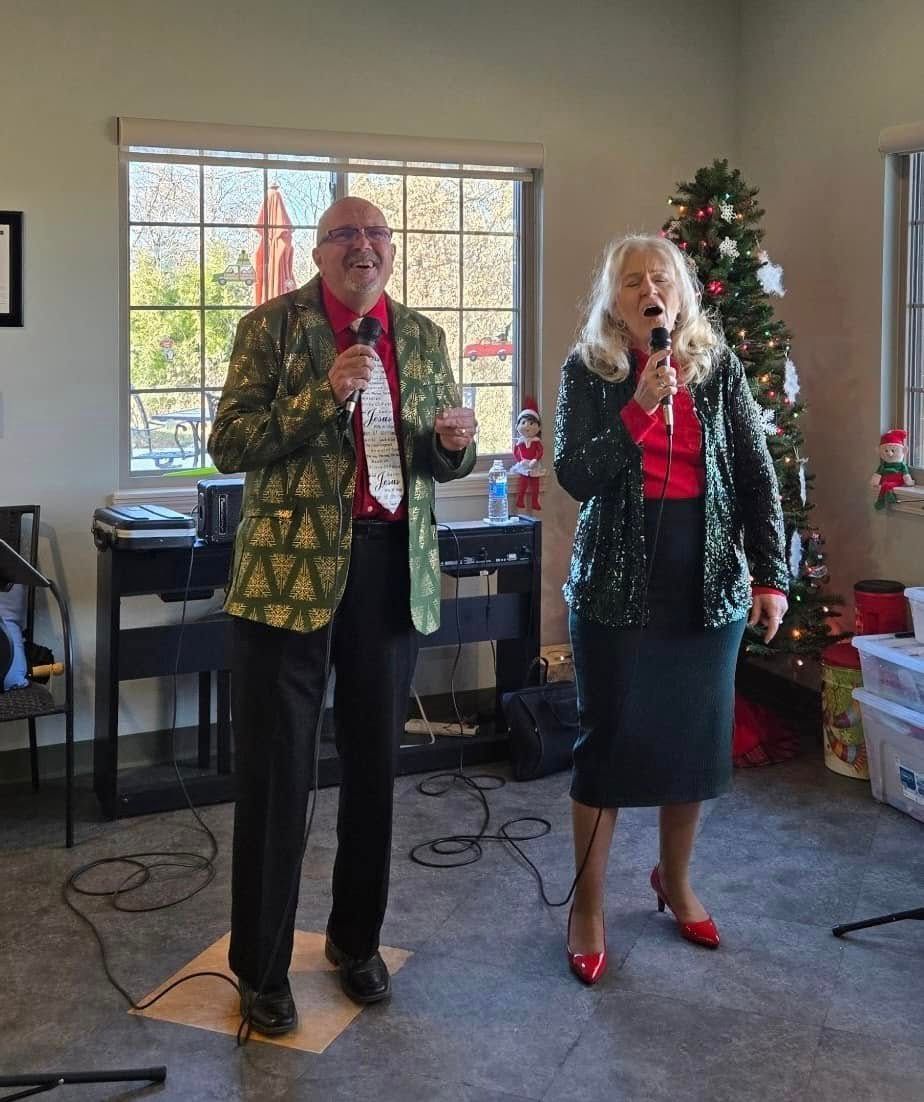 Person playing an acoustic guitar, fingers on frets. Red and green stage lighting.