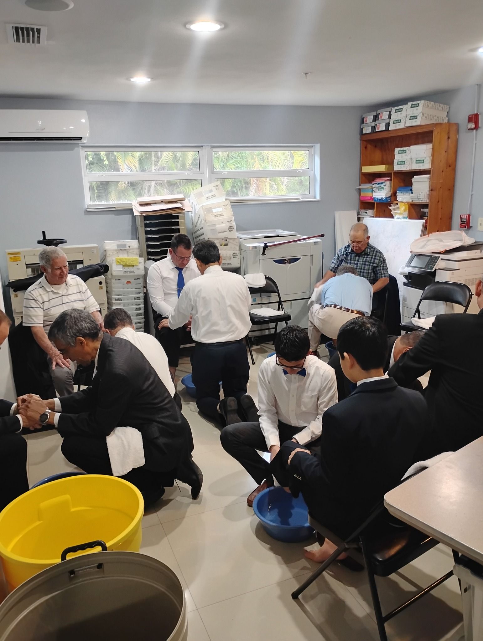 A group of men are kneeling down in a room with buckets of water.