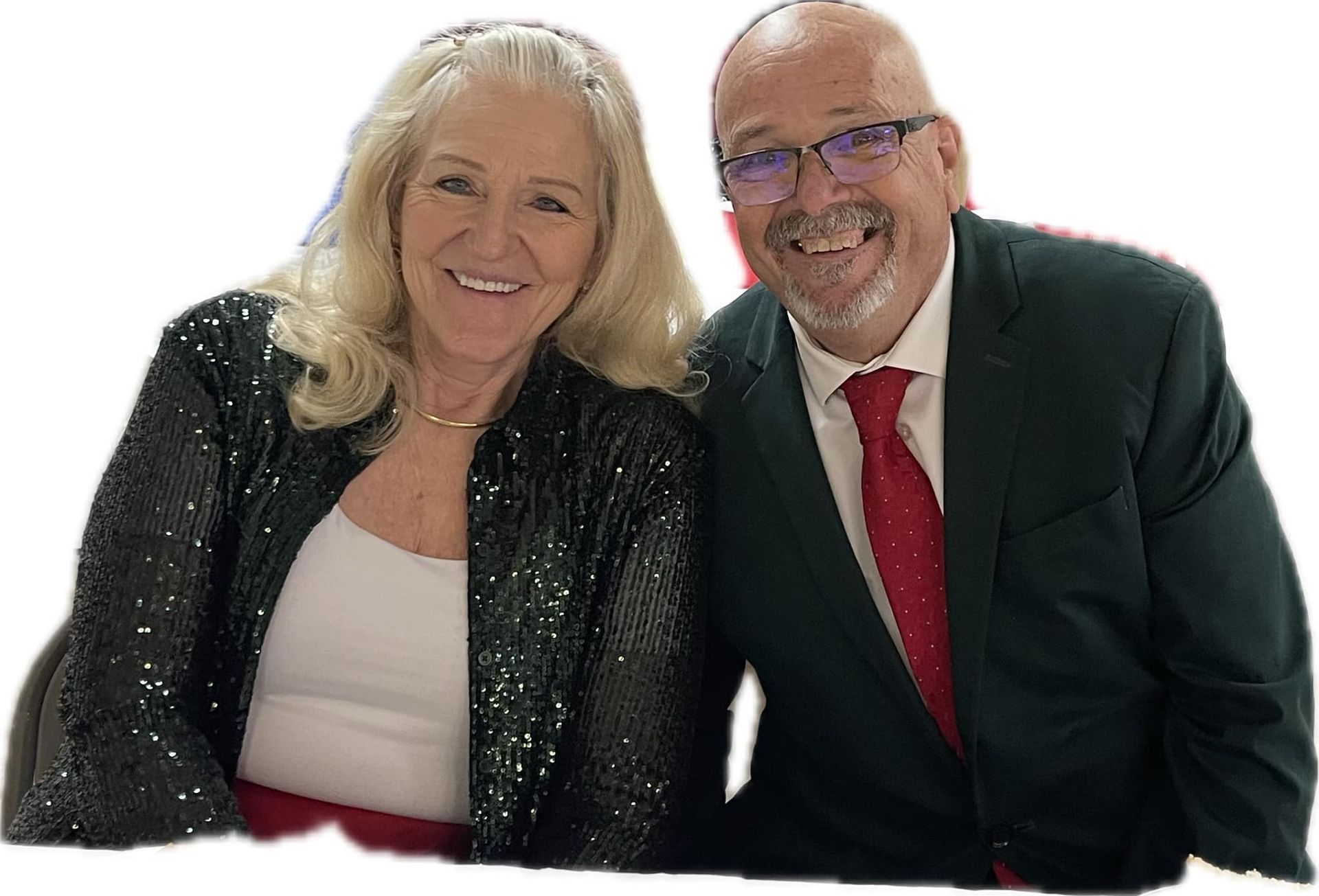 Woman with blonde hair and sequined jacket, and man in a suit smiling together.