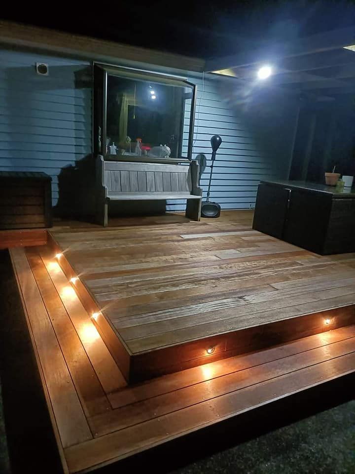 A wooden deck with lights on it is lit up at night.