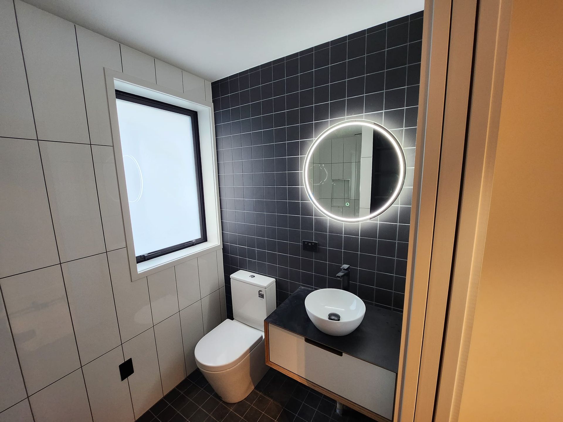 A bathroom with a toilet , sink and mirror.