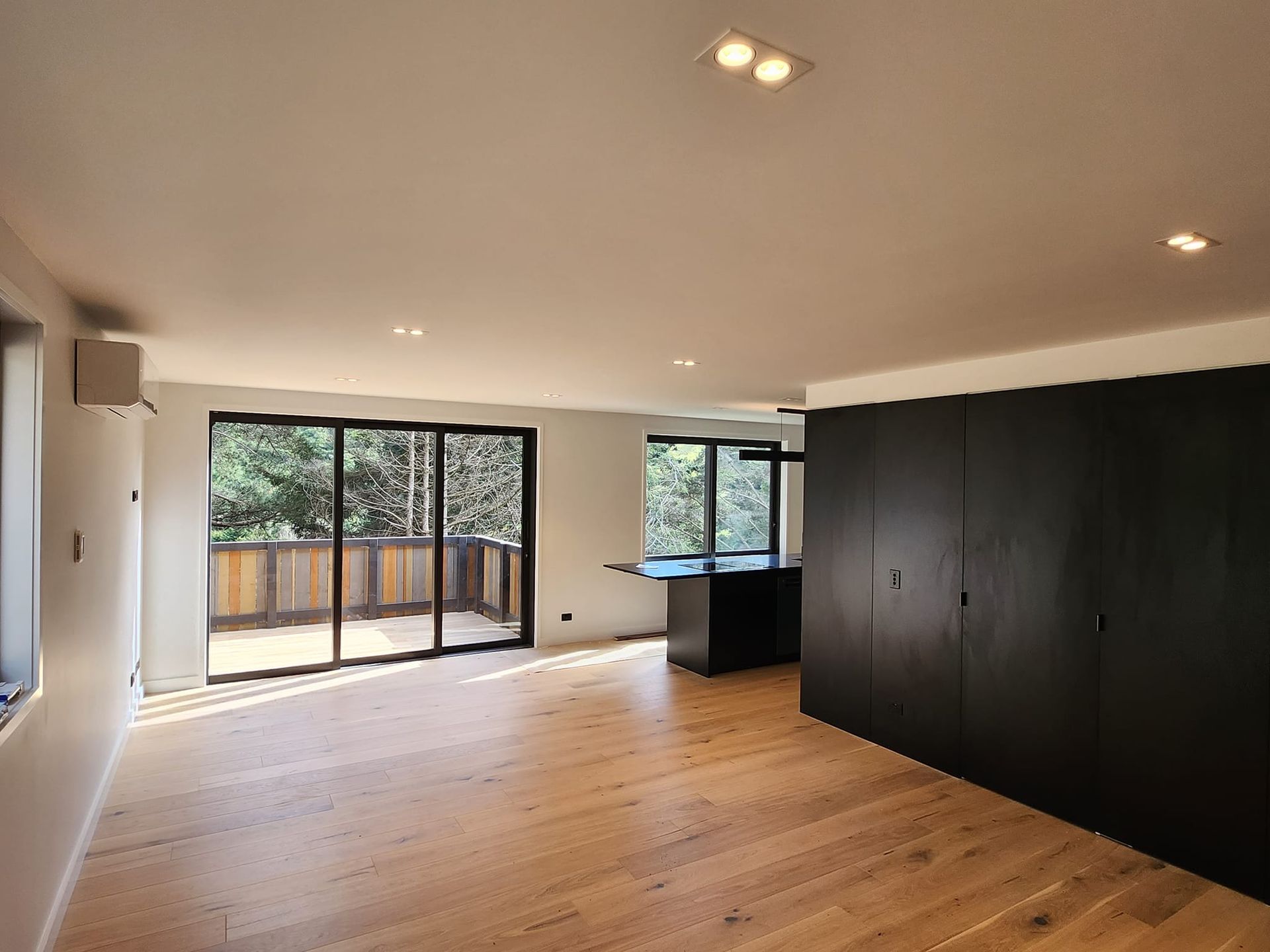 An empty living room with hardwood floors and sliding glass doors