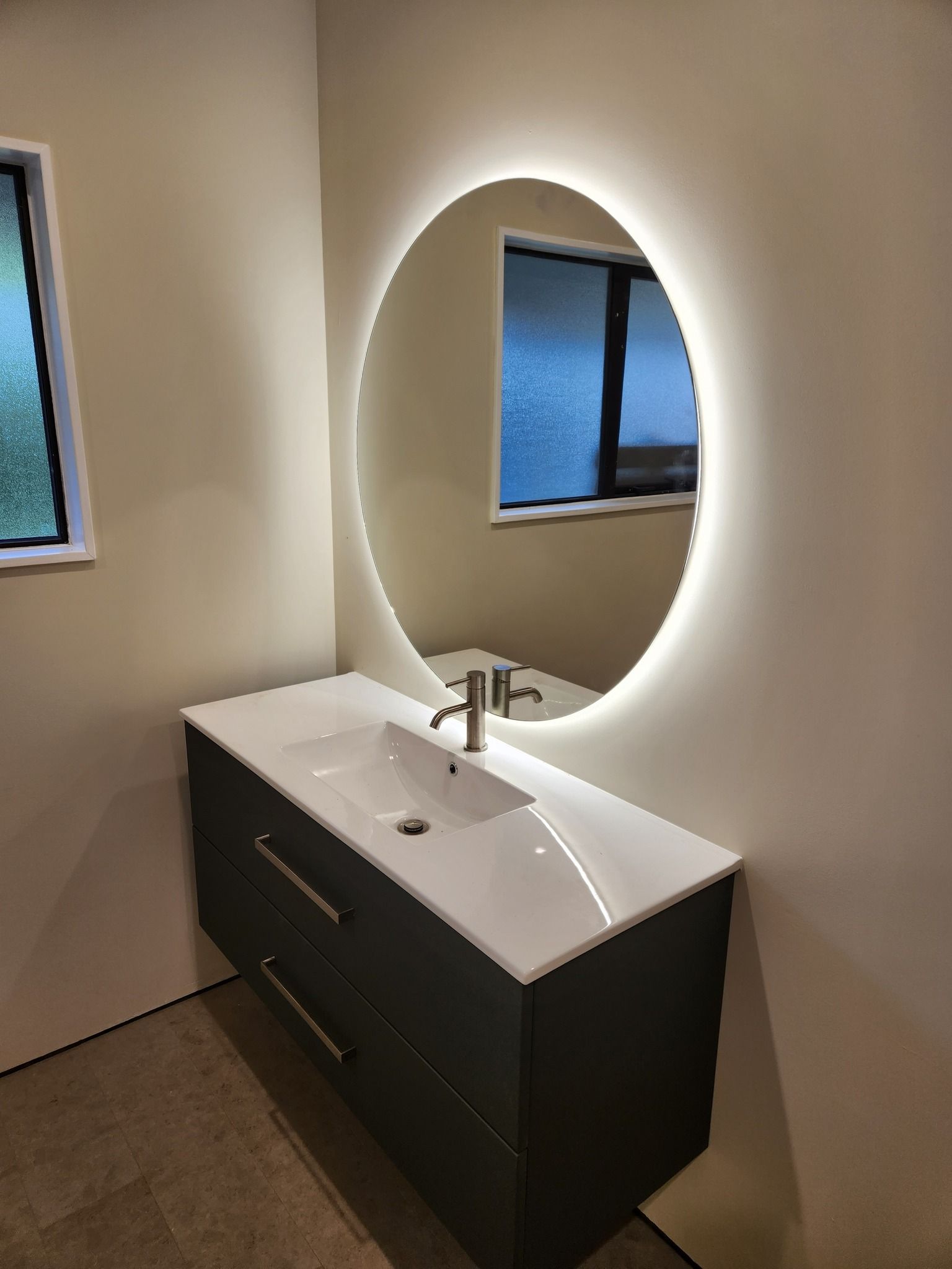 A bathroom with a sink and a round mirror.
