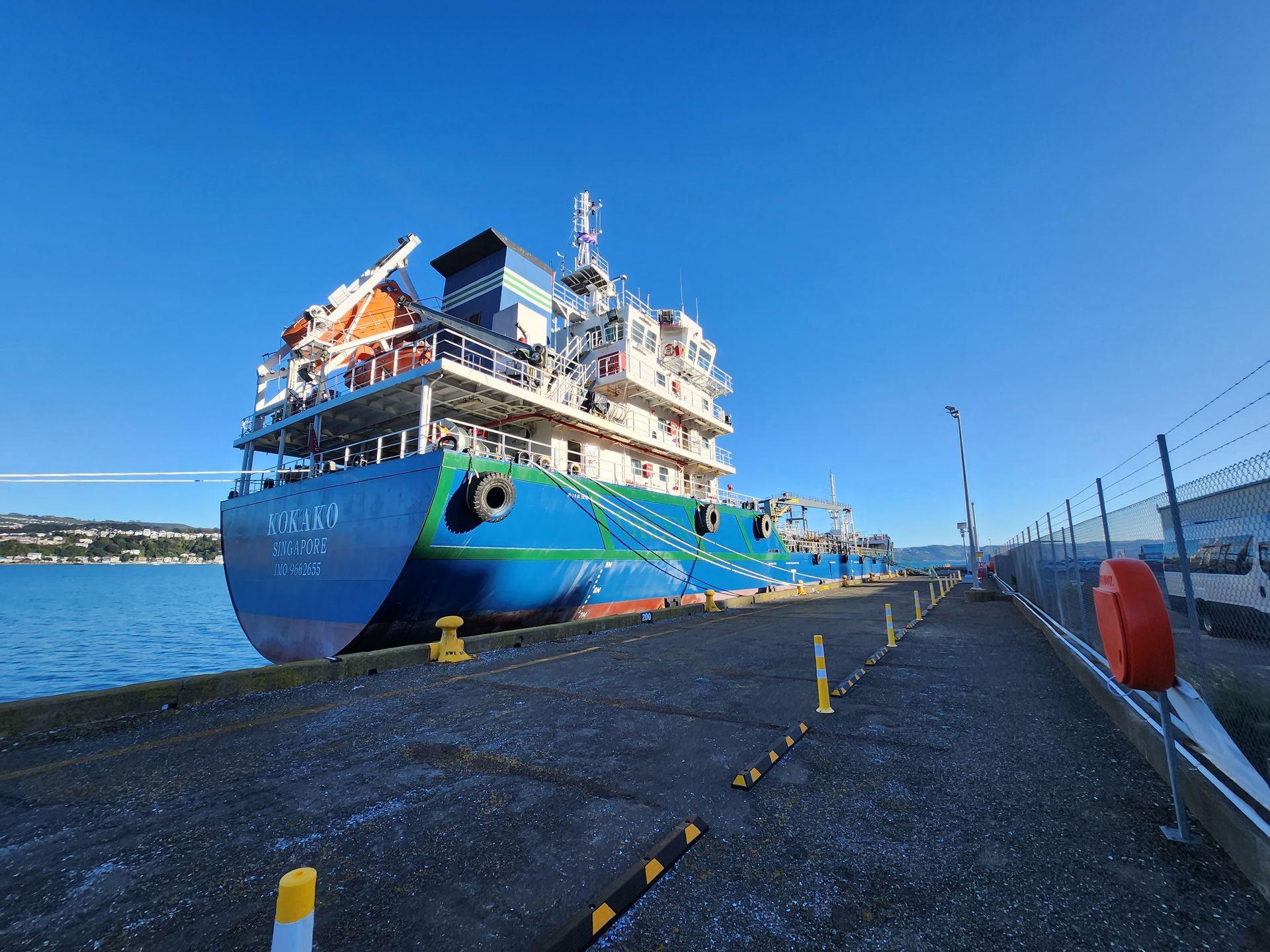 A man wearing a hard hat and safety vest is working on a machine.