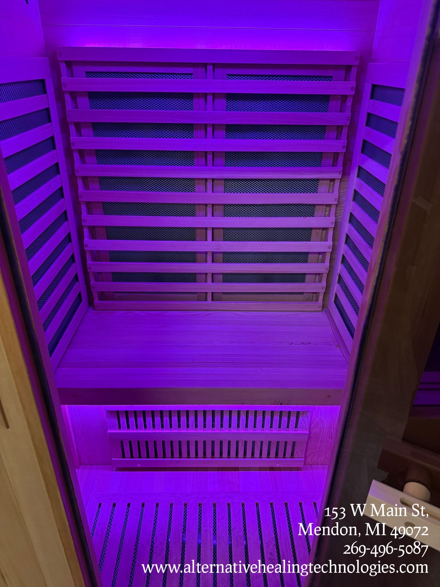 Purple-lit infrared sauna interior with wooden benches and panels.
