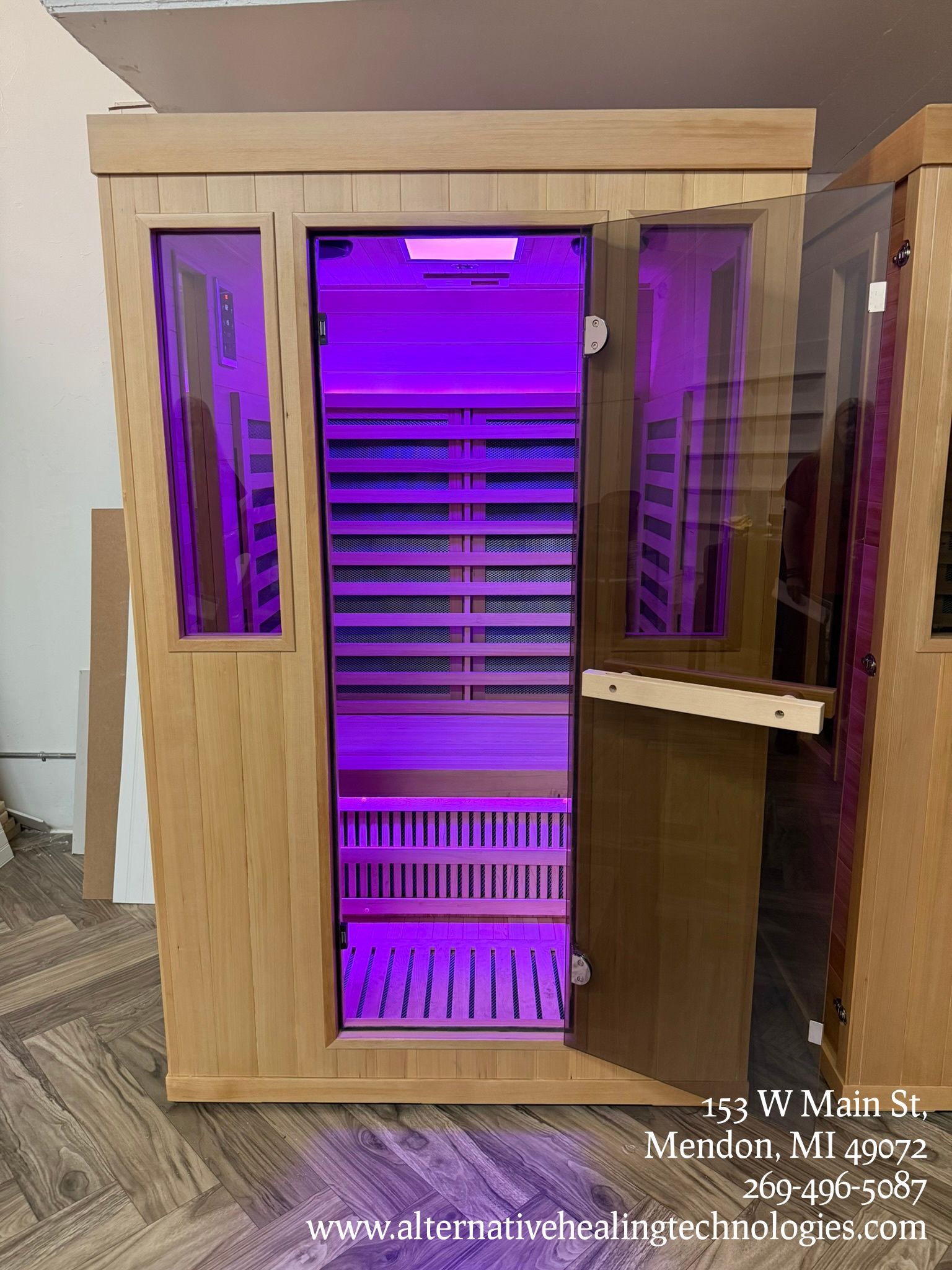 Wooden sauna with purple interior lighting, door ajar.