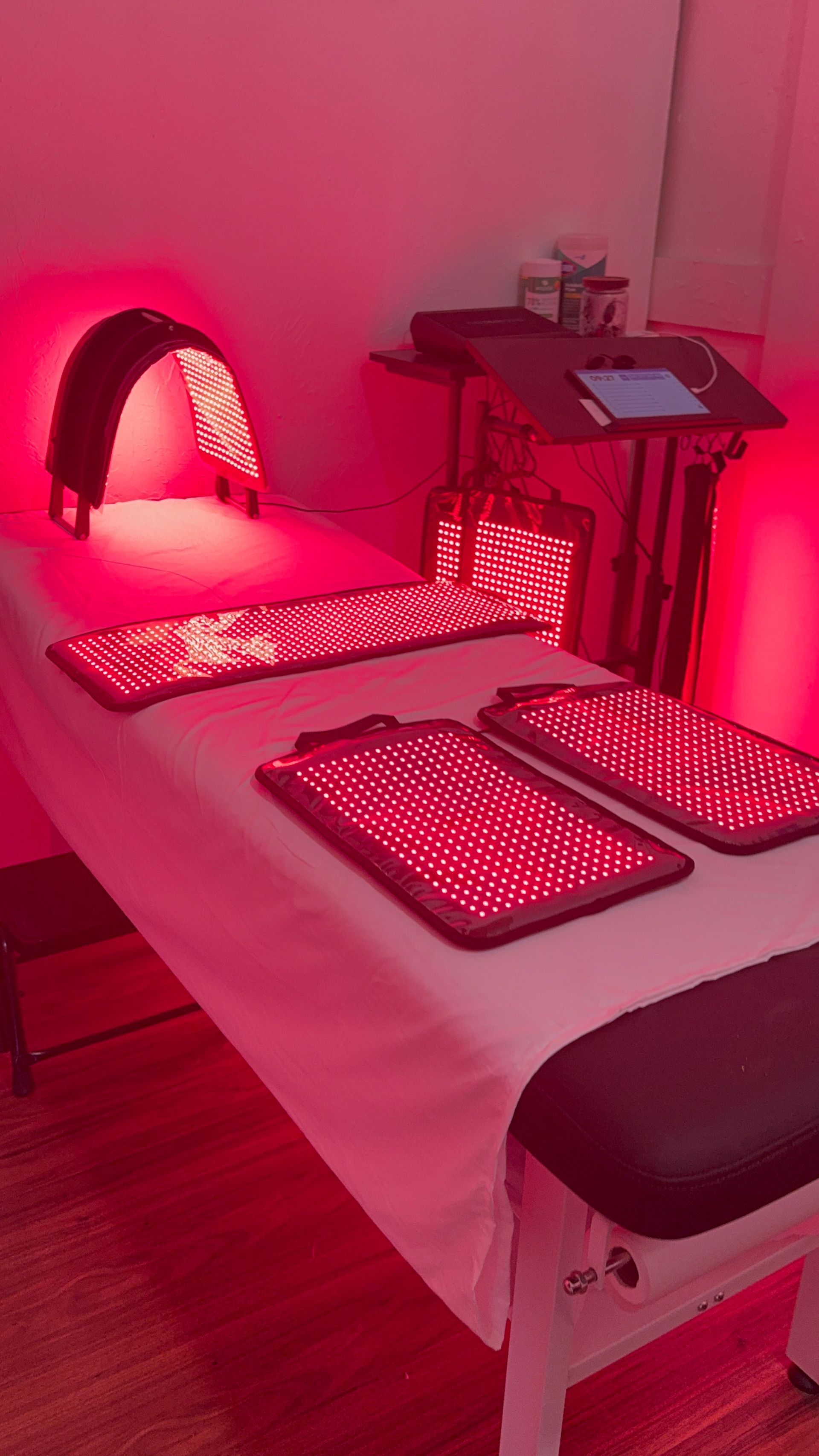 Red light therapy bed with a large arch and several panels emitting red light.
