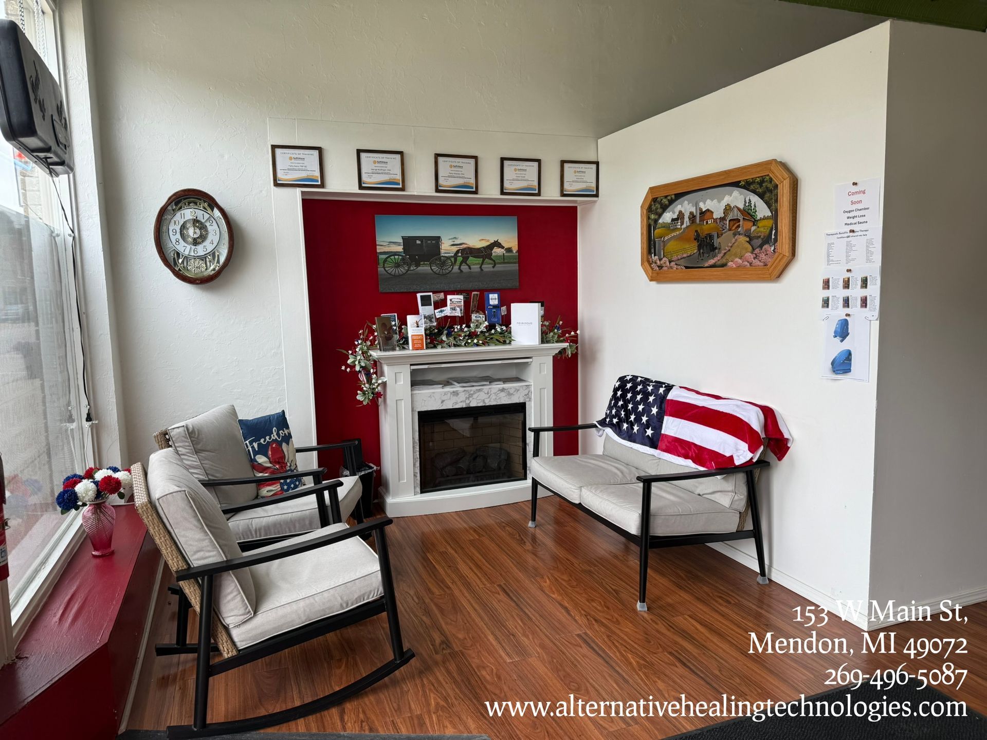 Waiting room with red accent wall, fireplace, chairs, and an American flag.