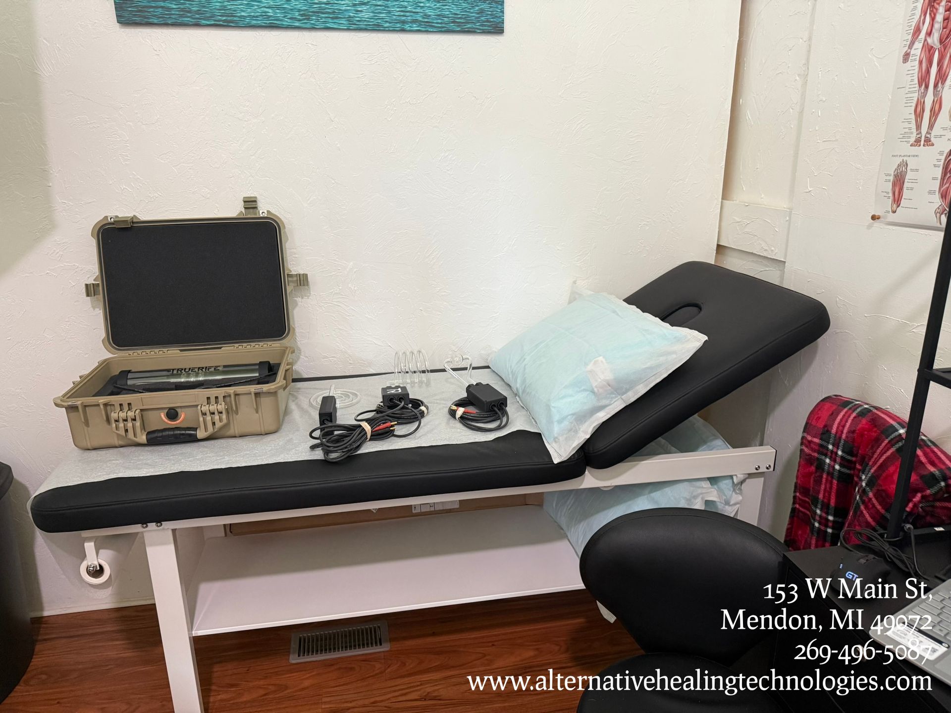 Treatment room with massage table, medical equipment, and open case.