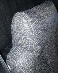 Gray crocodile-patterned car seat or headrest close-up inside a vehicle.