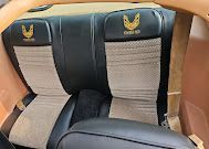 Black and beige car seat with gold logo on the headrests inside a tan interior