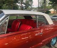 Red vintage convertible with a white roof and bright red interior parked outdoors.