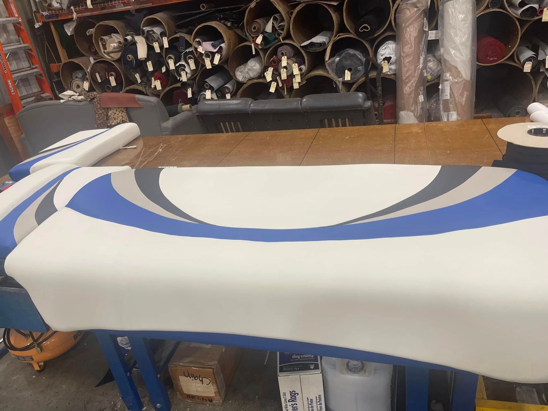 White board with blue curved stripes on a worktable in a workshop or storage area