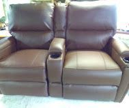 Brown leather recliner sofa with two seats and a center armrest, shown front view