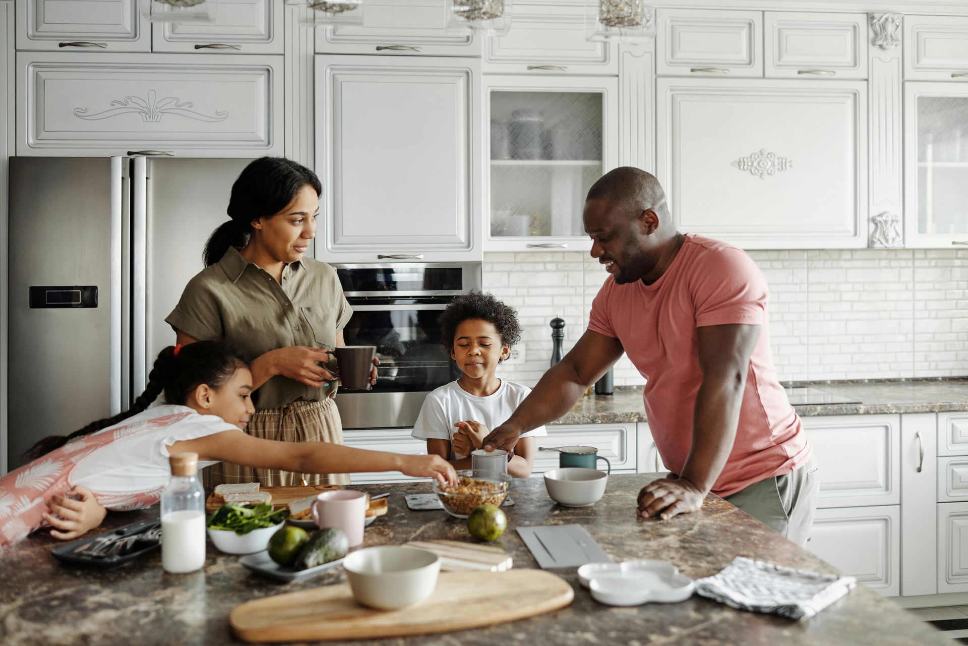 A family is sitting at a table in a kitchen preparing food.