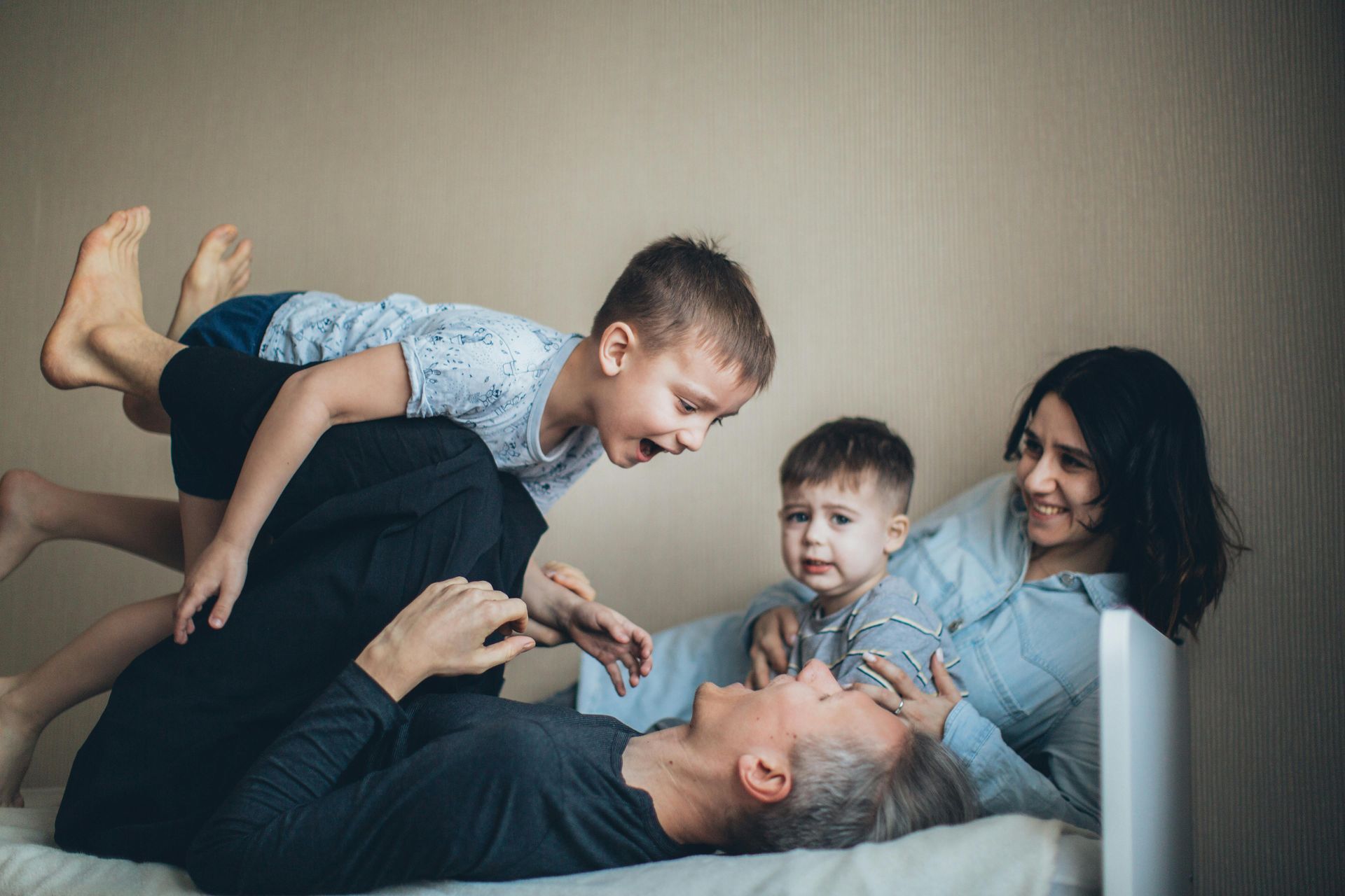 A family is laying on a bed and playing with each other.
