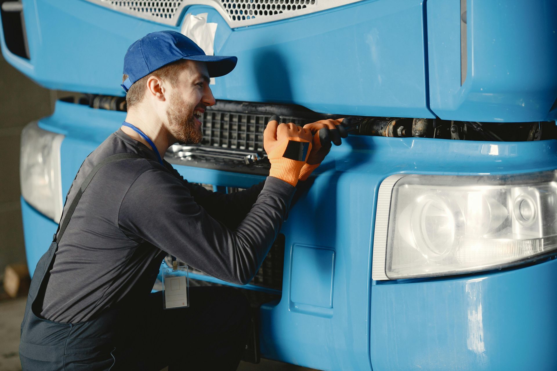 A man is working on the front of a blue truck.