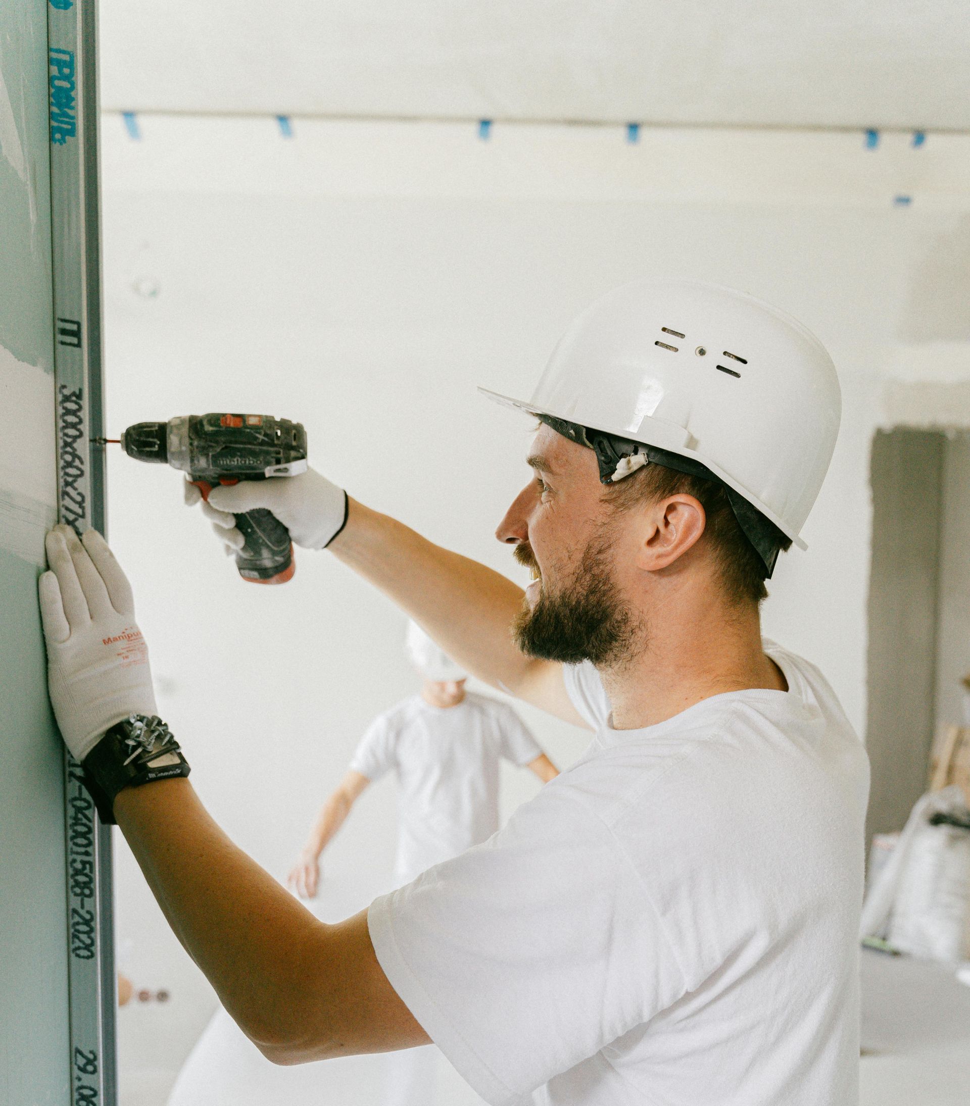 A man wearing a hard hat is using a drill on a wall