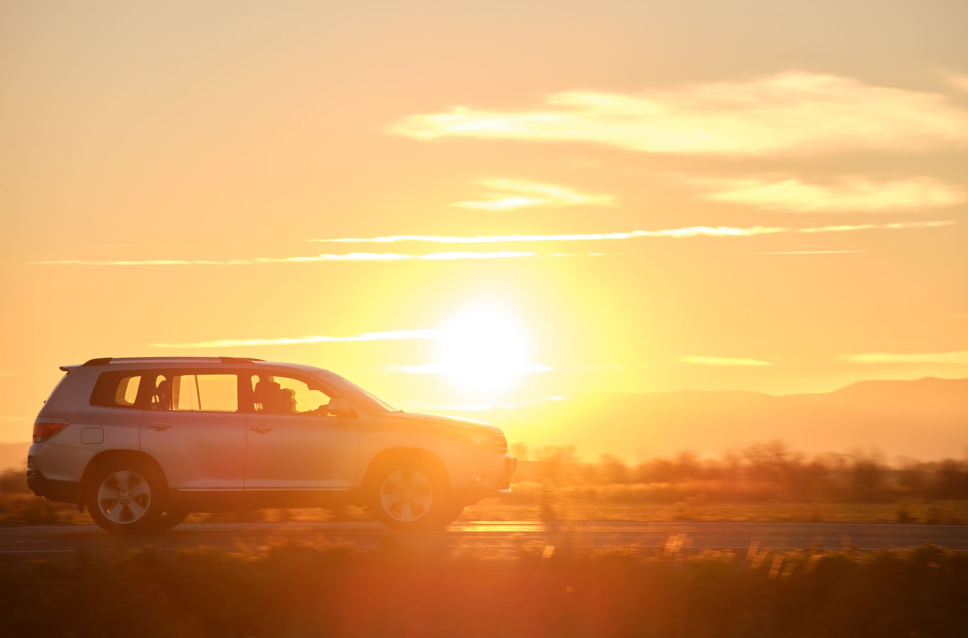 A car is parked on the side of the road at sunset.