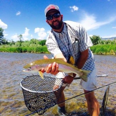 A man is holding a rainbow trout in a net