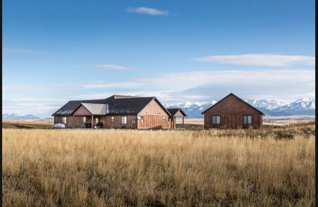 There are two houses in the middle of a field.