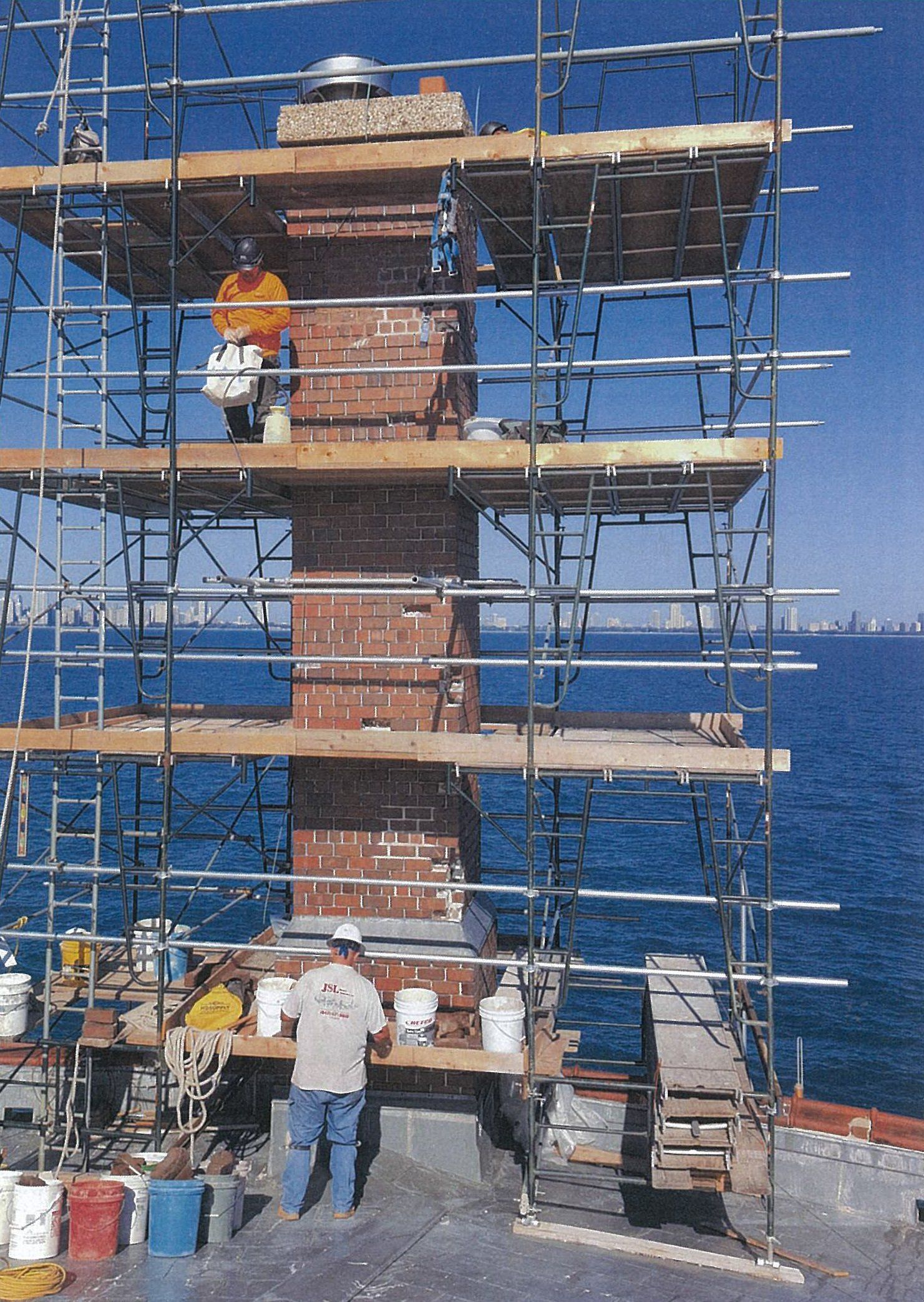 A man is standing on a scaffolding near the ocean