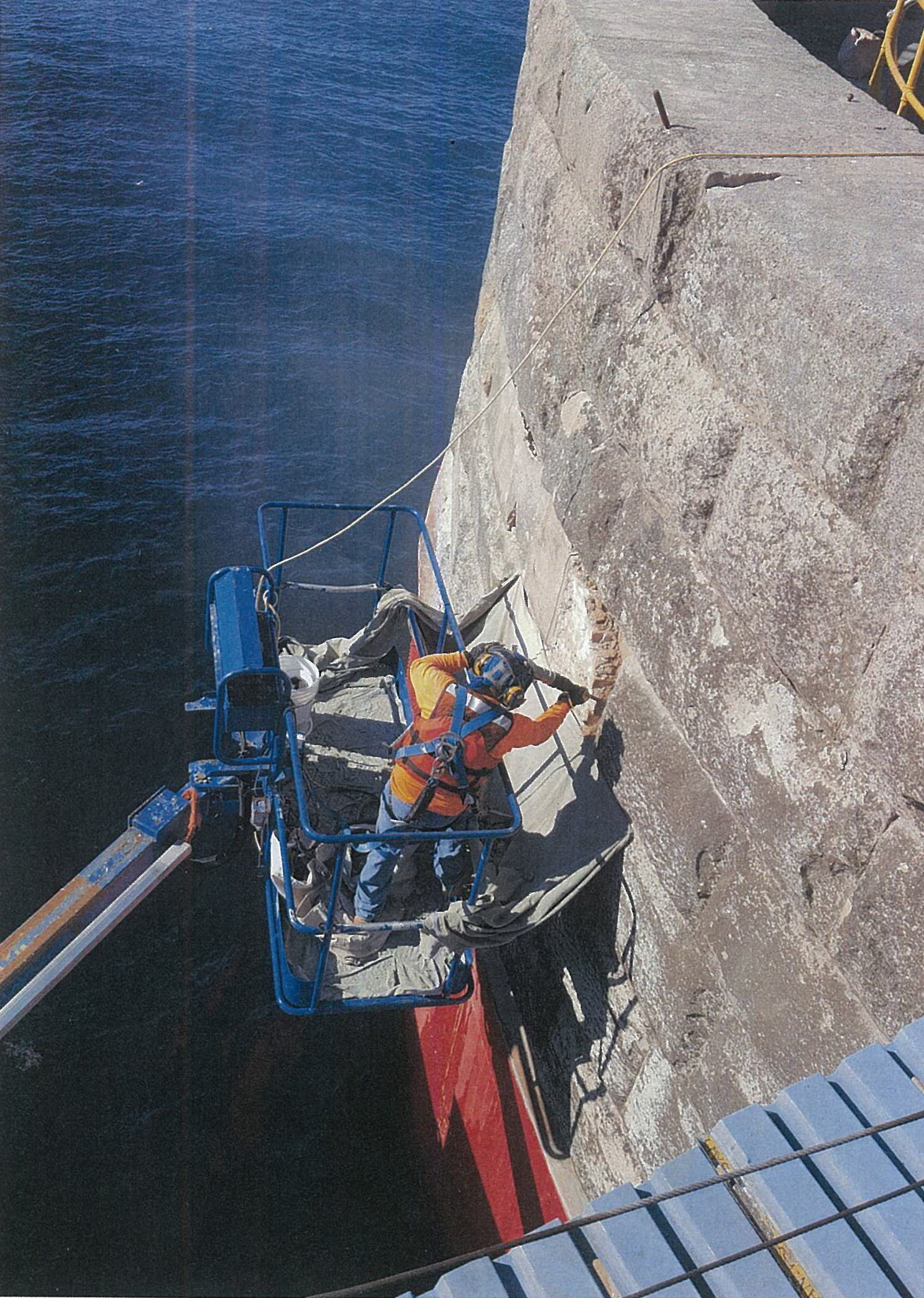 A man is working on a concrete wall with a crane