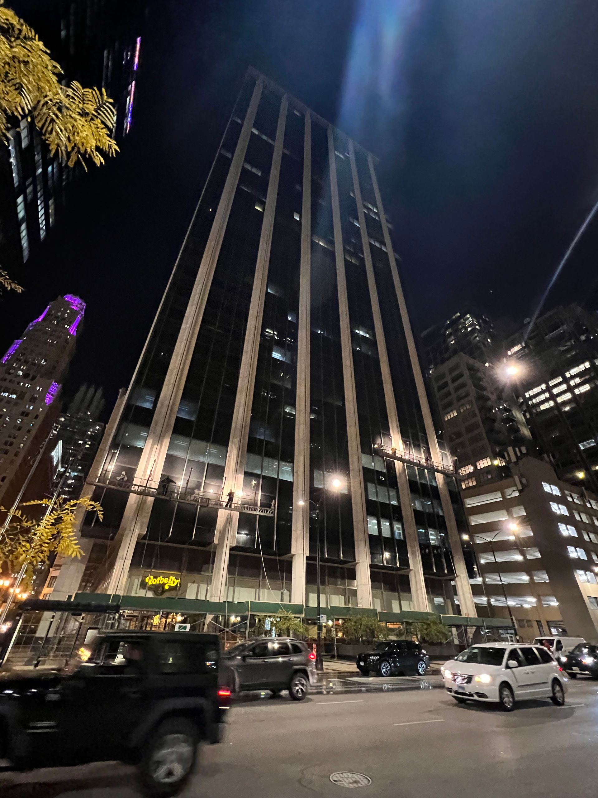 A jeep is parked in front of a tall building at night