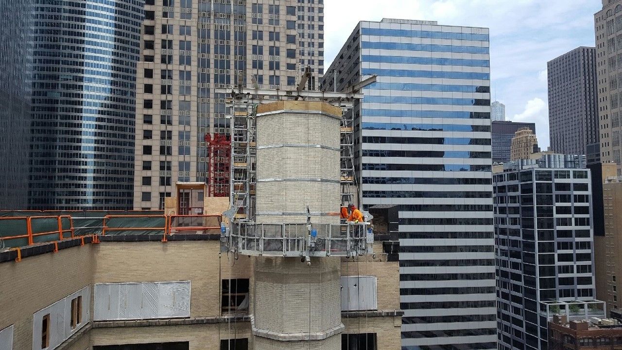 A group of construction workers are working on the side of a building.