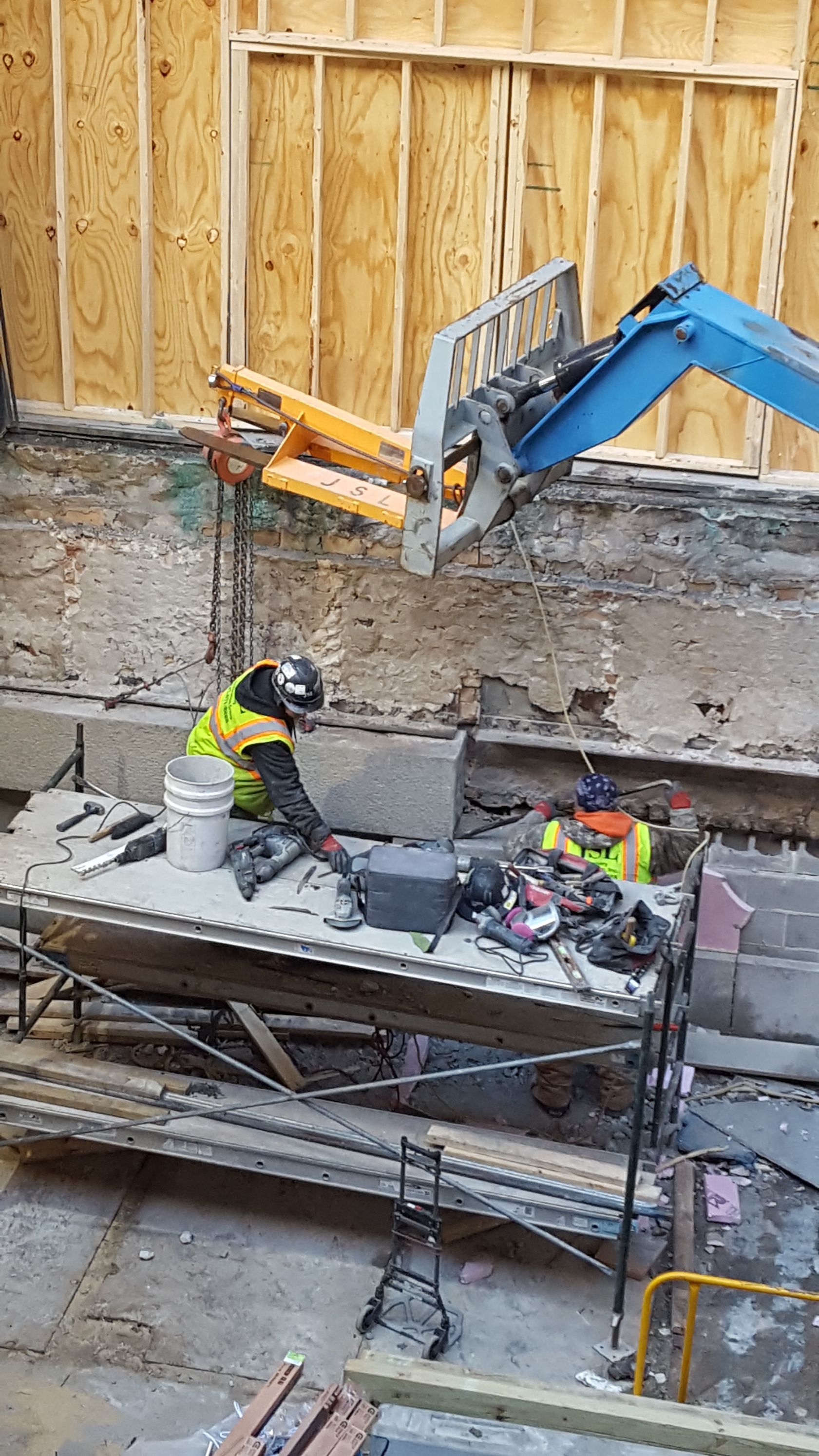 A construction worker is using a crane to lift a concrete slab.