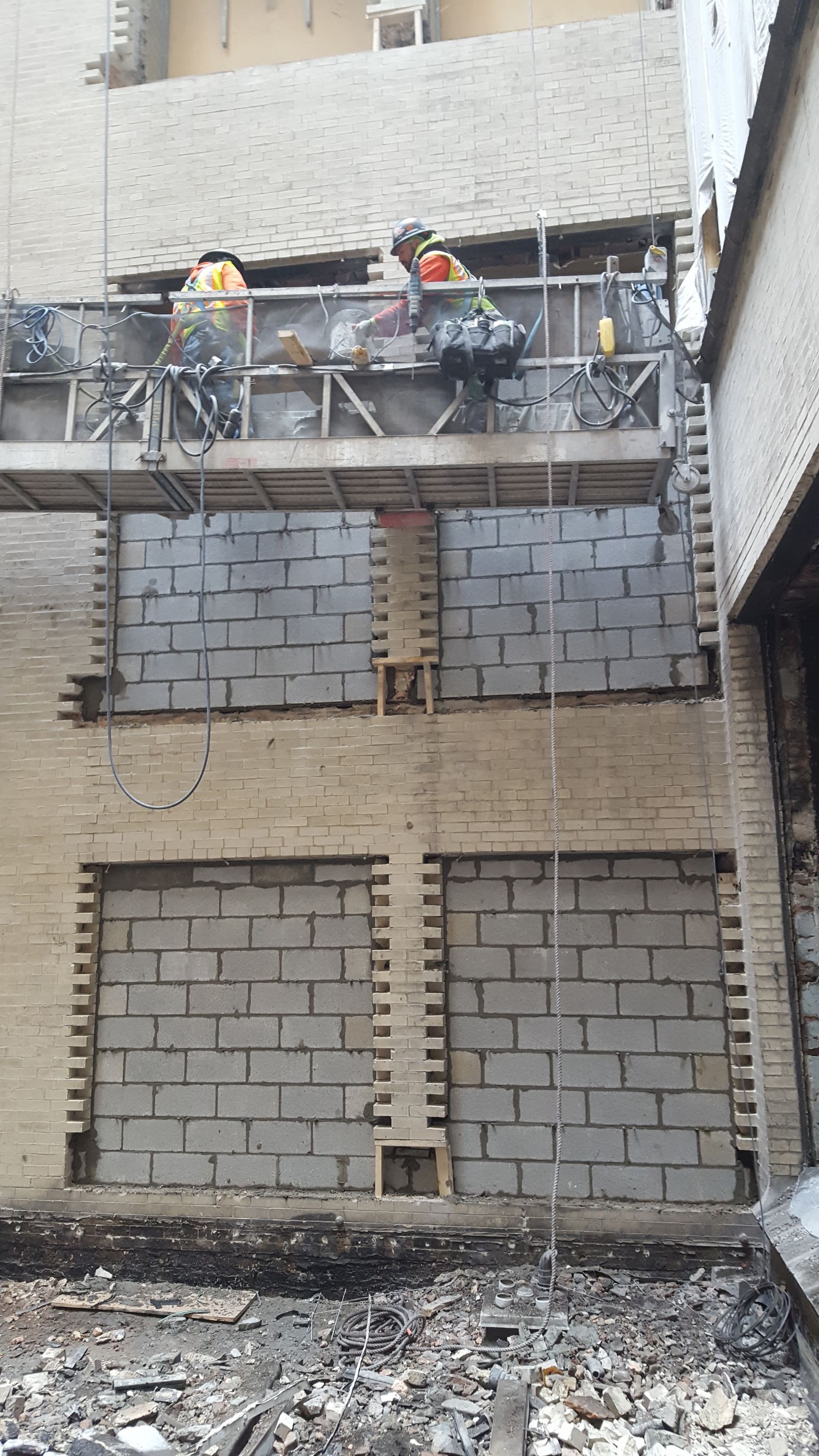 A group of construction workers are working on a brick wall.
