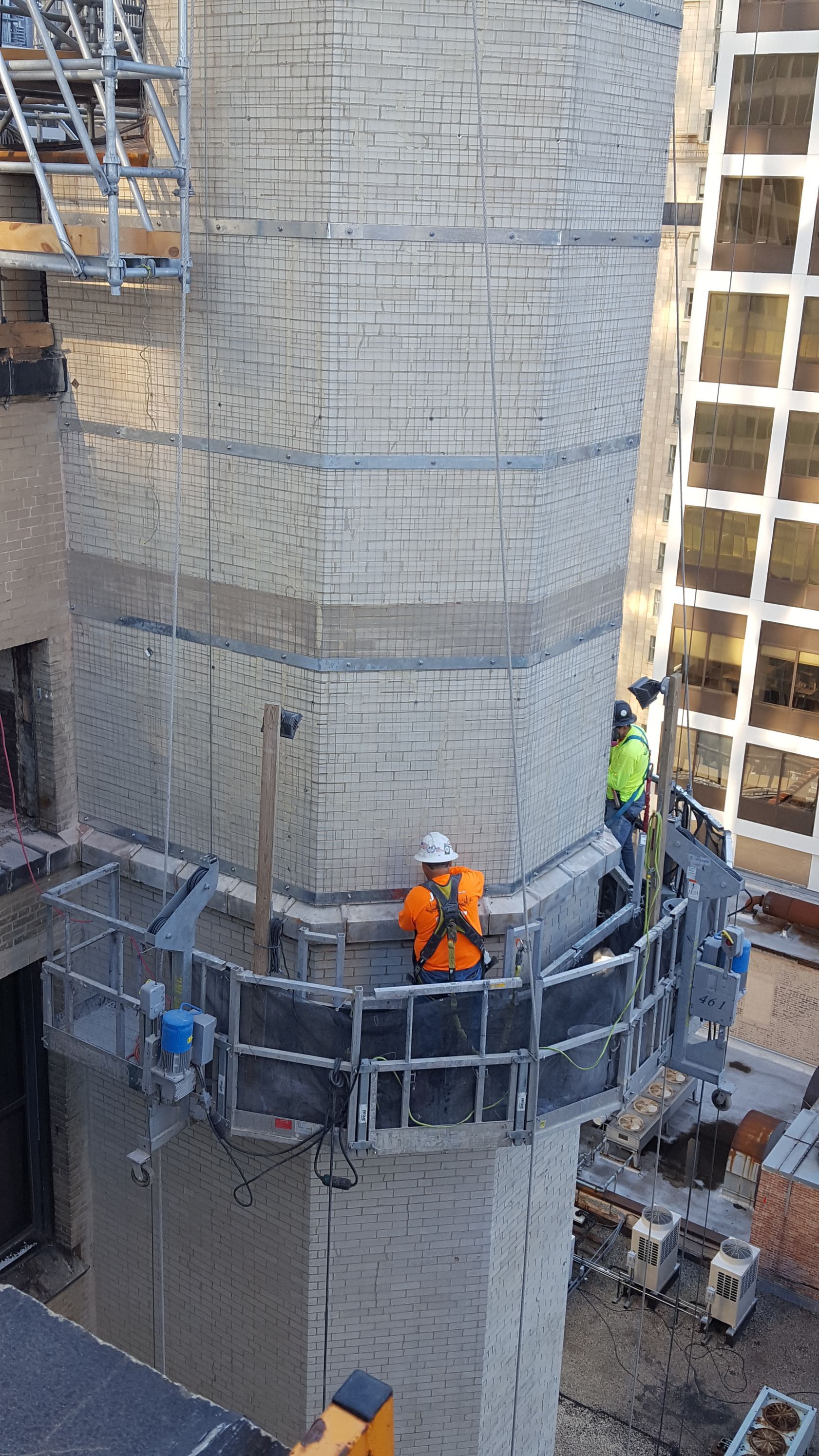 A group of construction workers are working on a brick building.