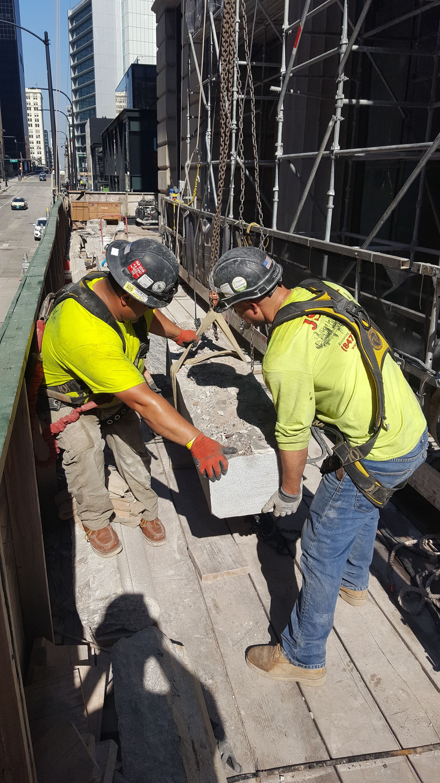 Two construction workers are working on a building on a scaffolding.