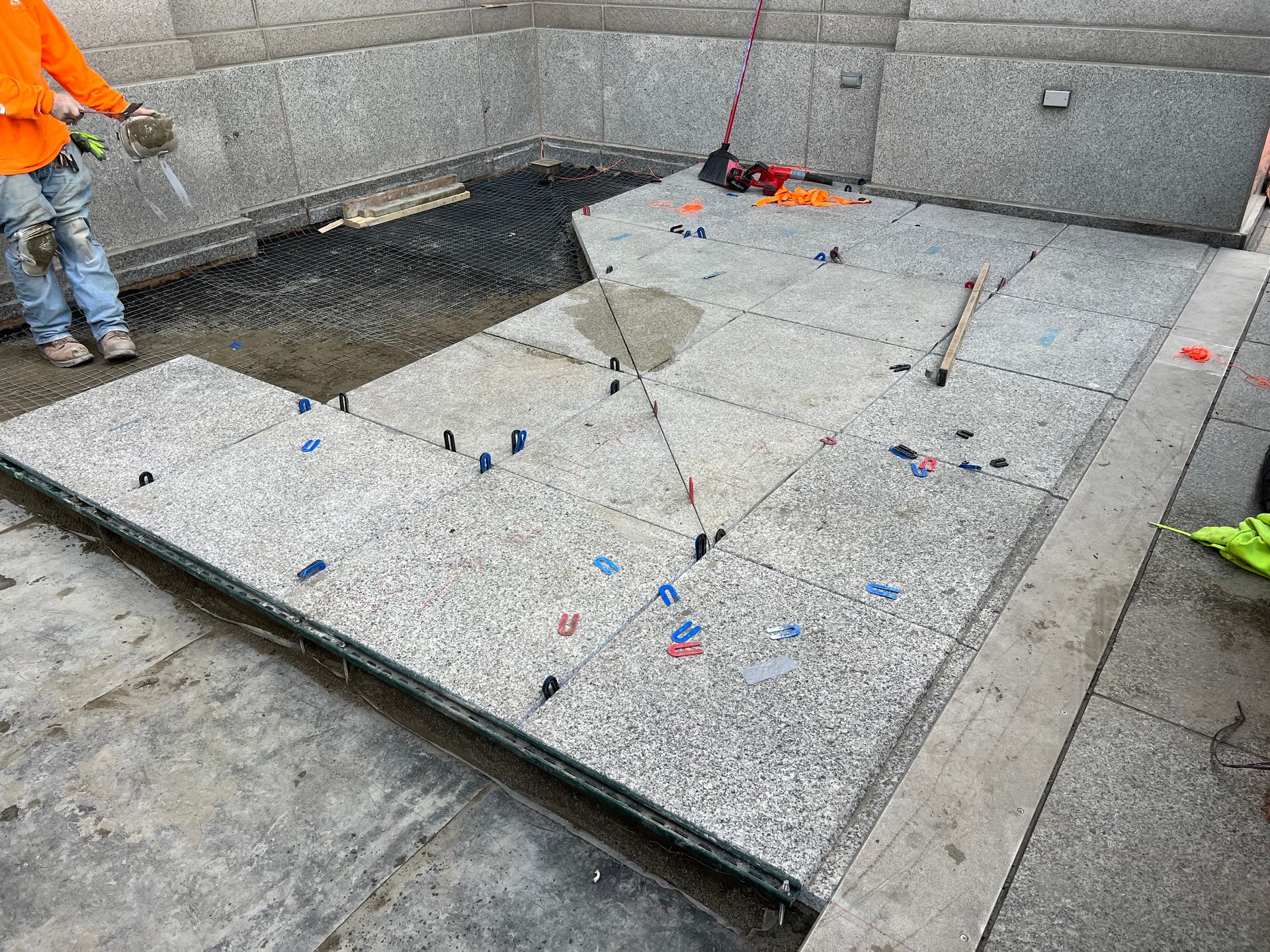 A man is laying tiles on a concrete floor.