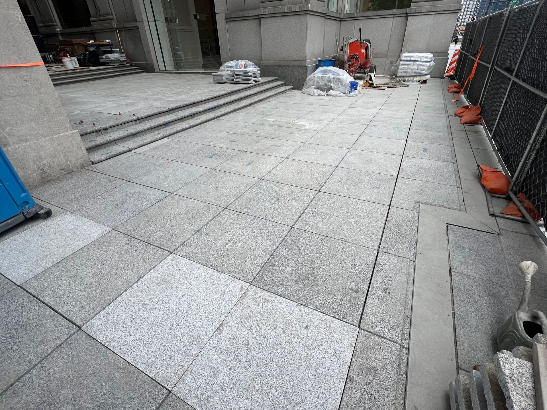 A tiled floor is being installed in front of a building.