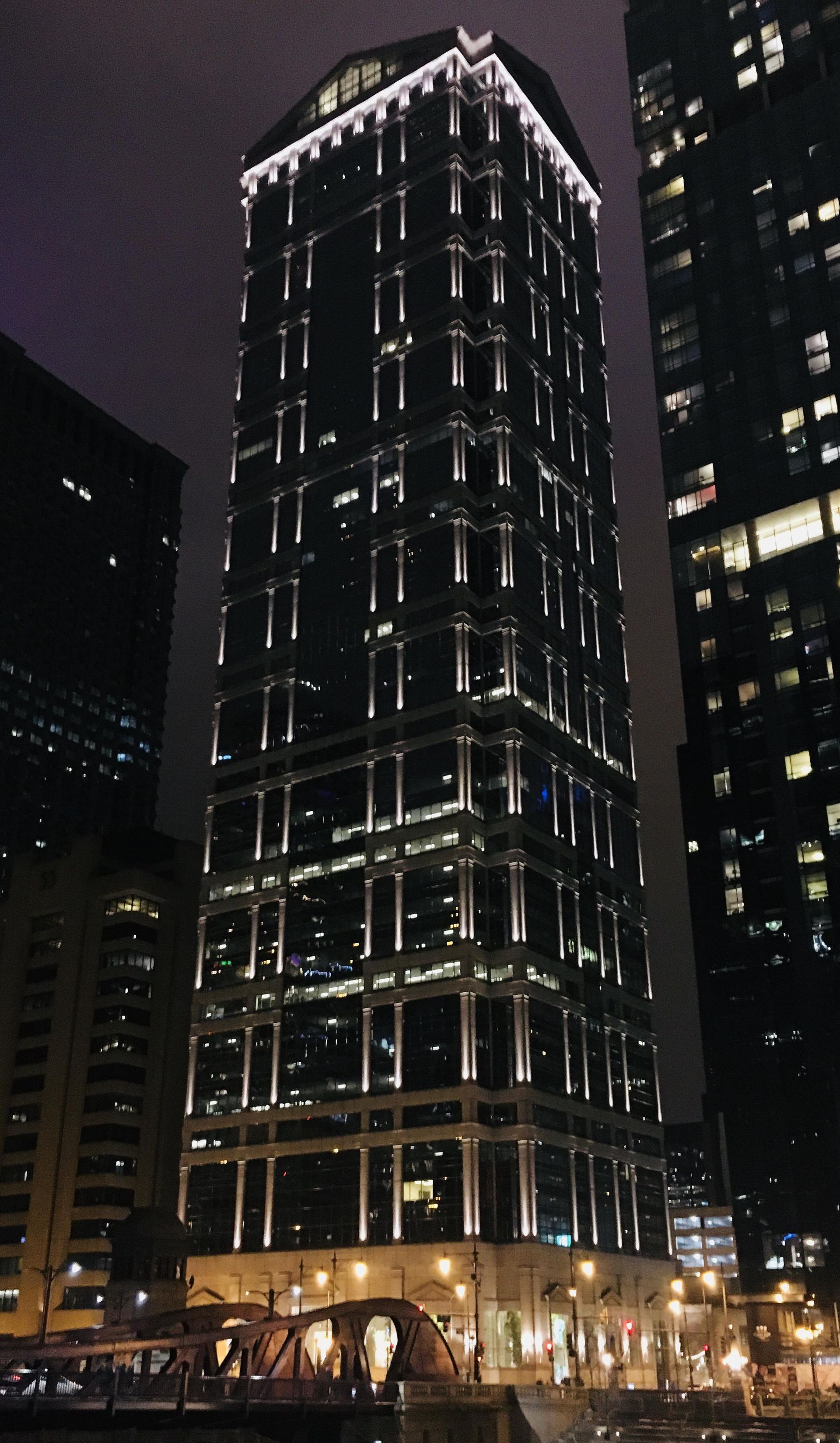A tall building is lit up at night in a city