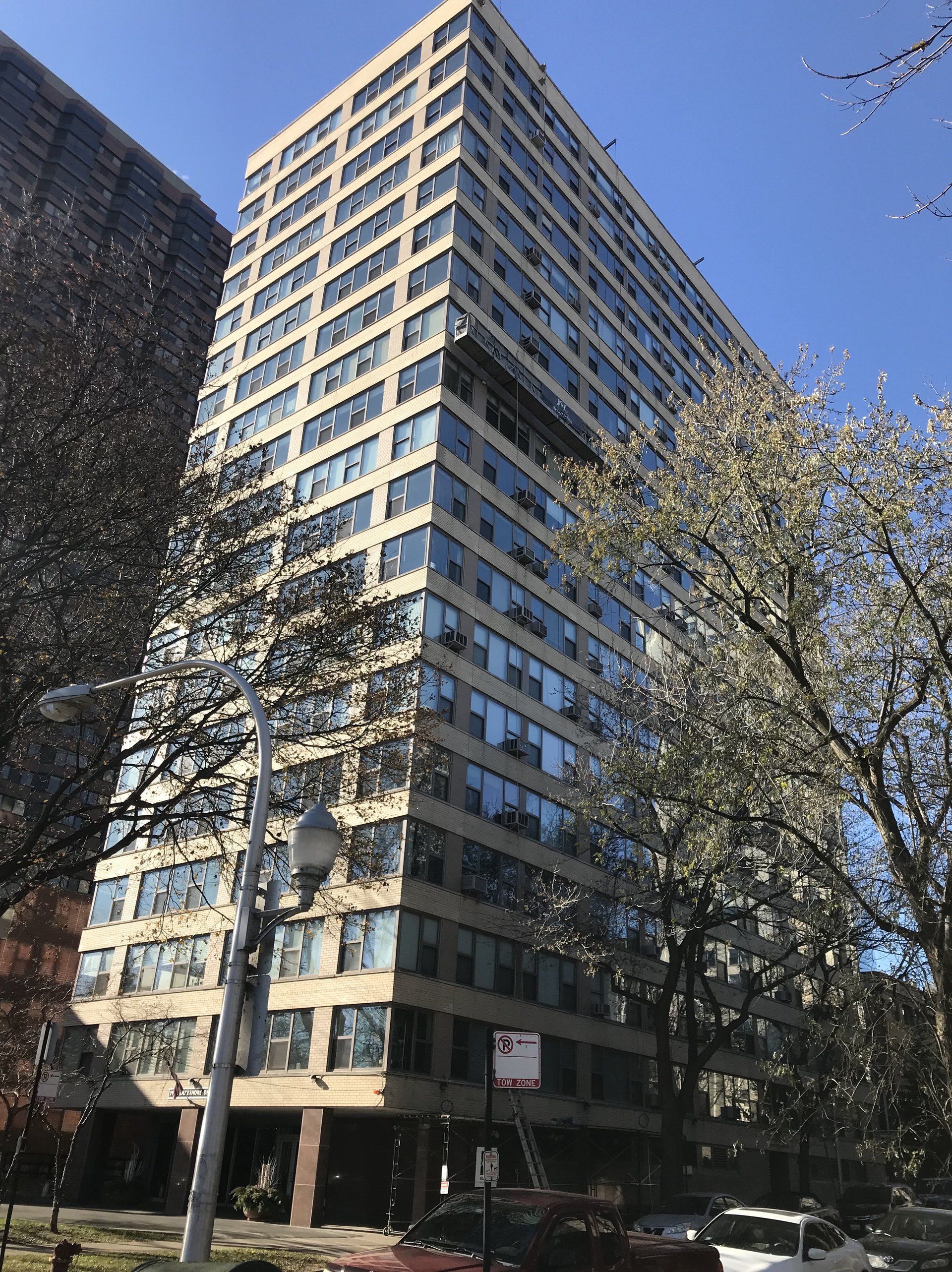 A tall building with a lot of windows is surrounded by trees.