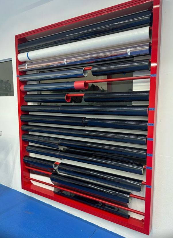 Un estante rojo lleno de rollos de plástico en una pared.