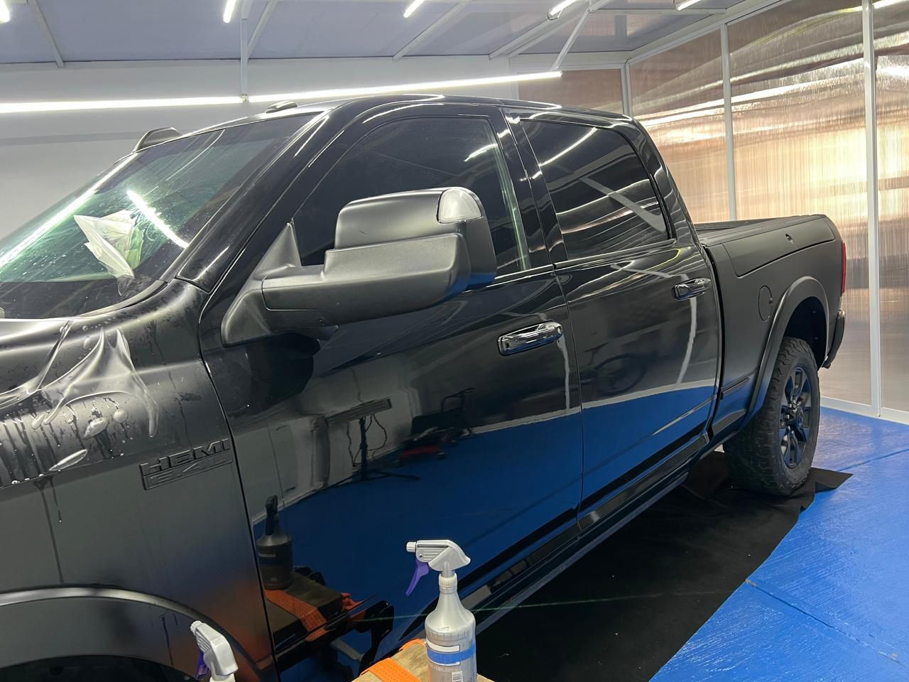 Un camión negro está estacionado encima de una alfombra azul en un garaje.