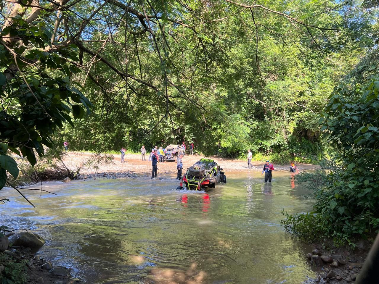 Un coche está atascado en un río rodeado de árboles.