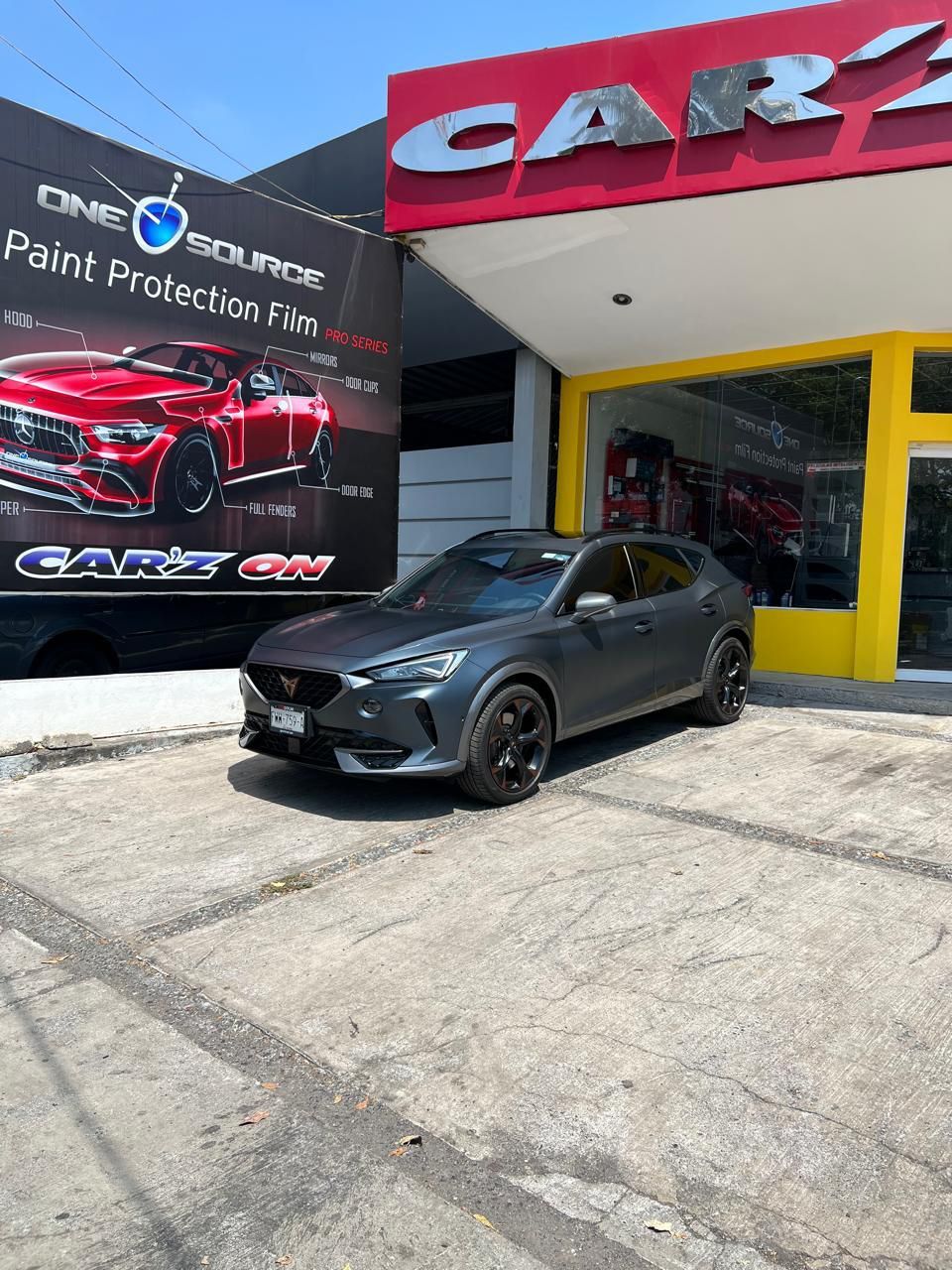 Un coche está aparcado delante de un concesionario de automóviles.