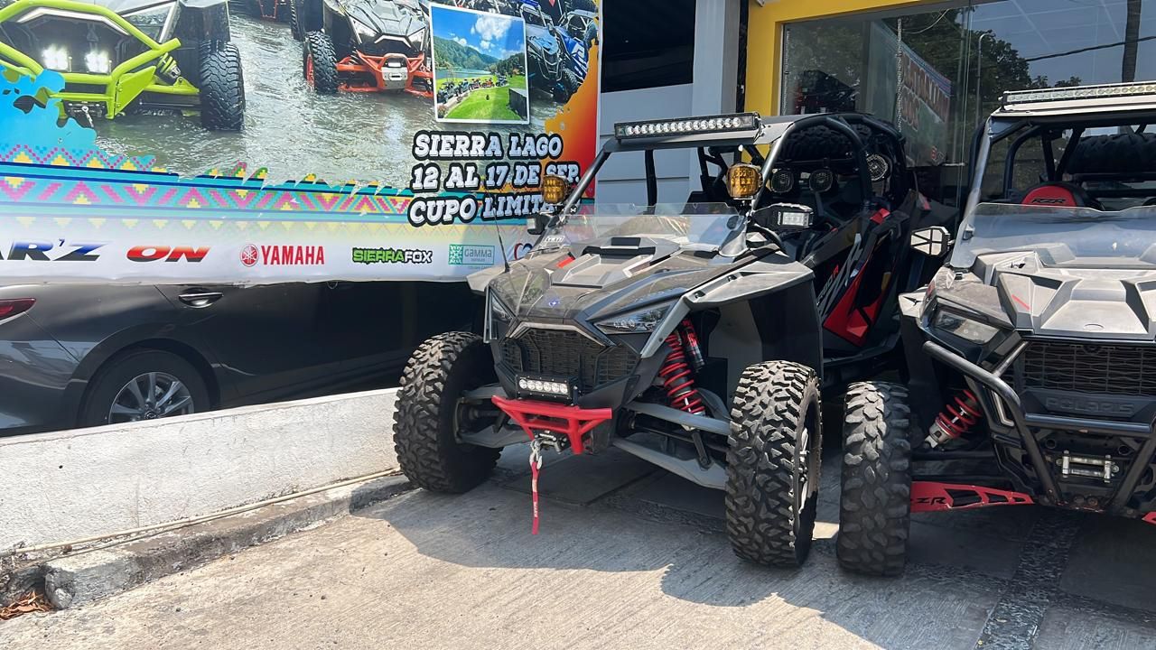 Dos vehículos todo terreno están estacionados al costado de la carretera frente a un edificio.