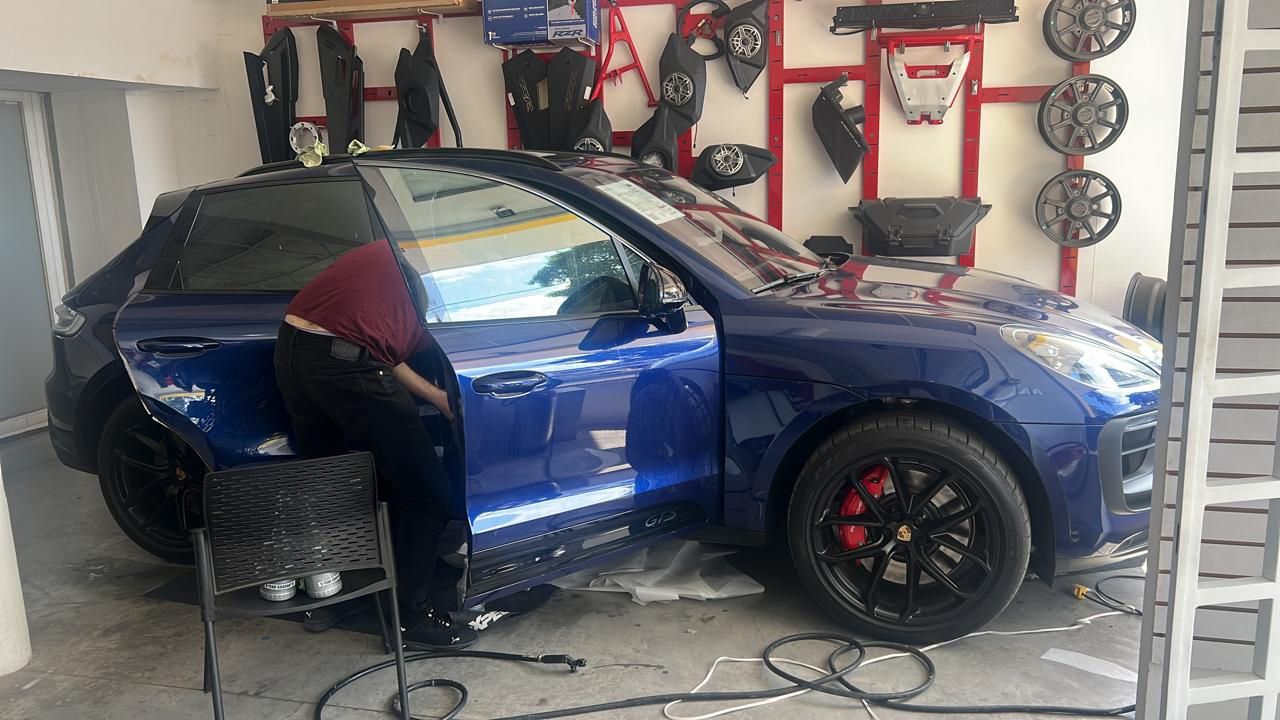Un hombre está trabajando en un coche azul en un garaje.
