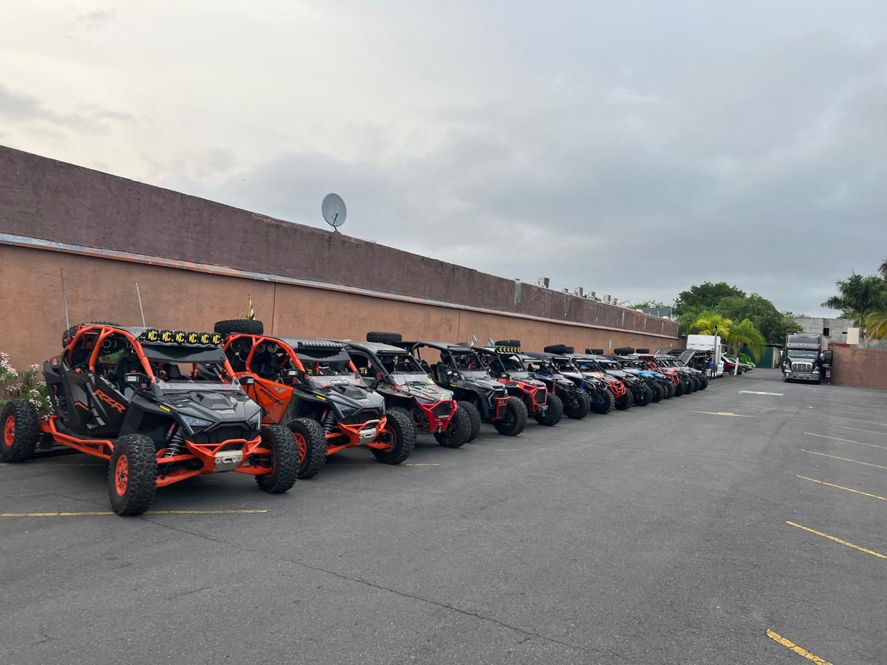 Una fila de buggies están estacionados en un estacionamiento frente a un edificio.