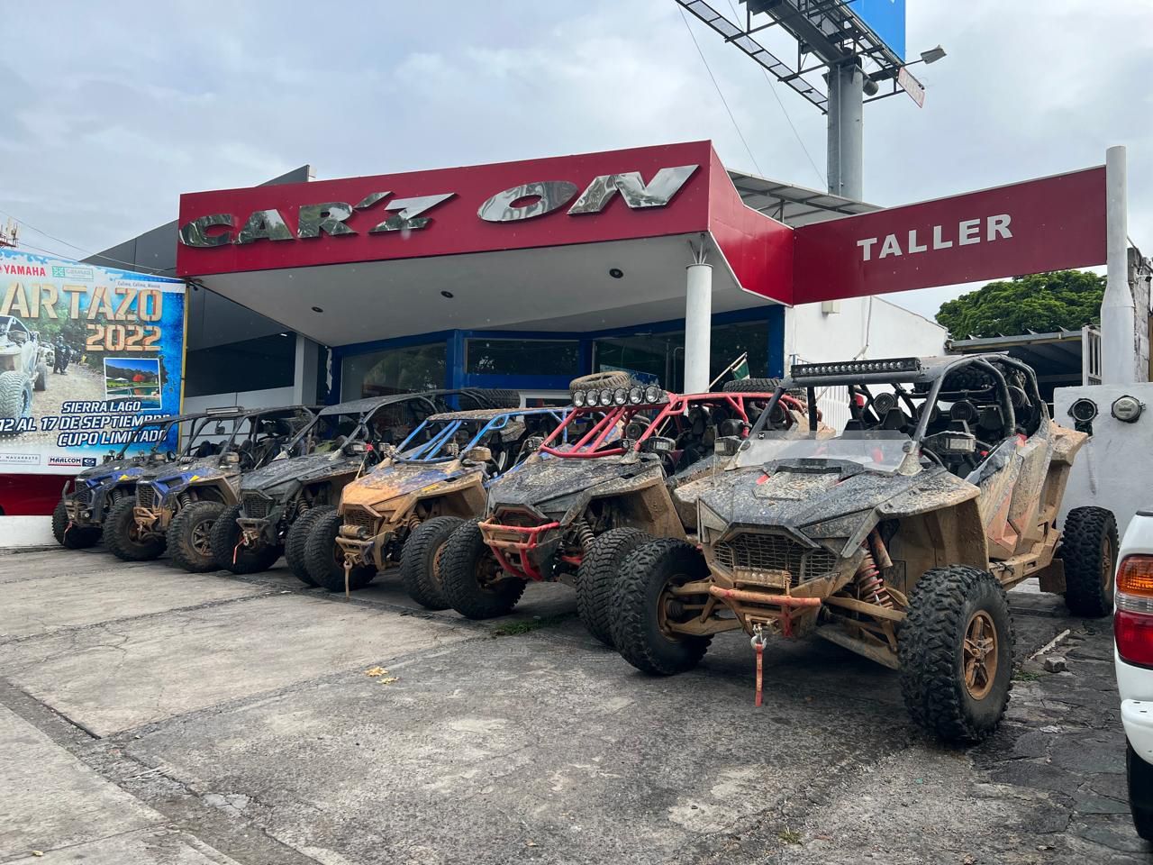 Una fila de vehículos todo terreno están estacionados frente a un concesionario de automóviles.