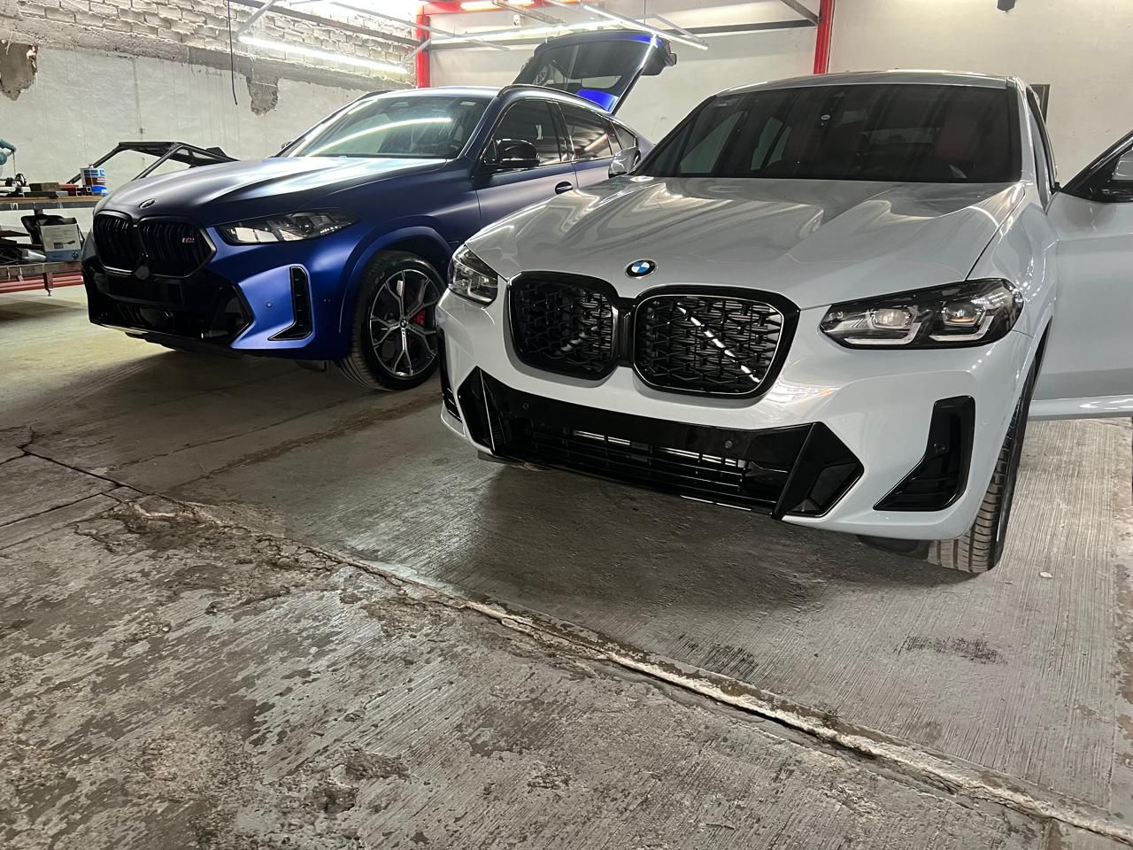 Dos coches están aparcados uno al lado del otro en un garaje.