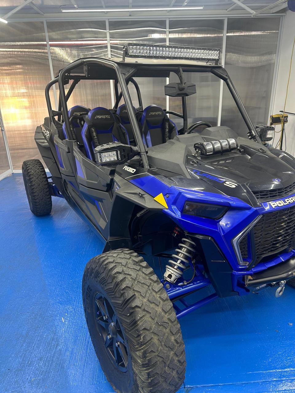 Un vehículo todo terreno azul y negro está estacionado en un piso azul en un garaje.