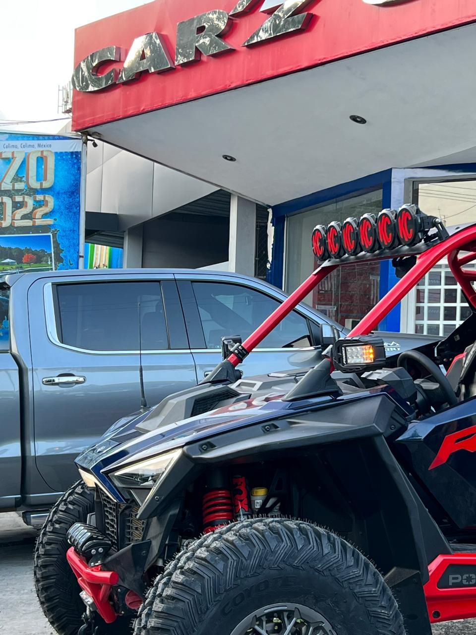 Dos vehículos todo terreno están estacionados frente a un concesionario de automóviles.