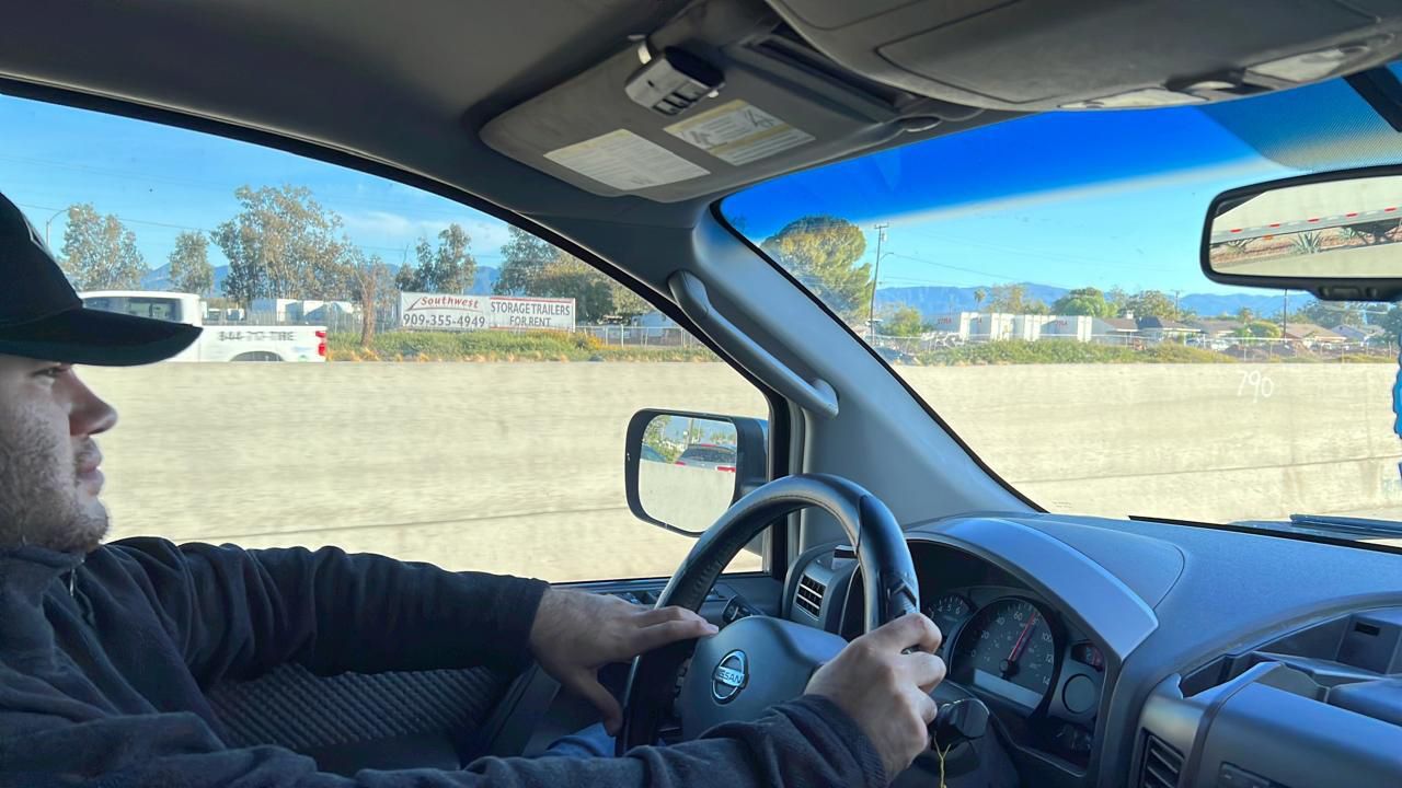 Un hombre que lleva un sombrero de vaquero conduce un coche.