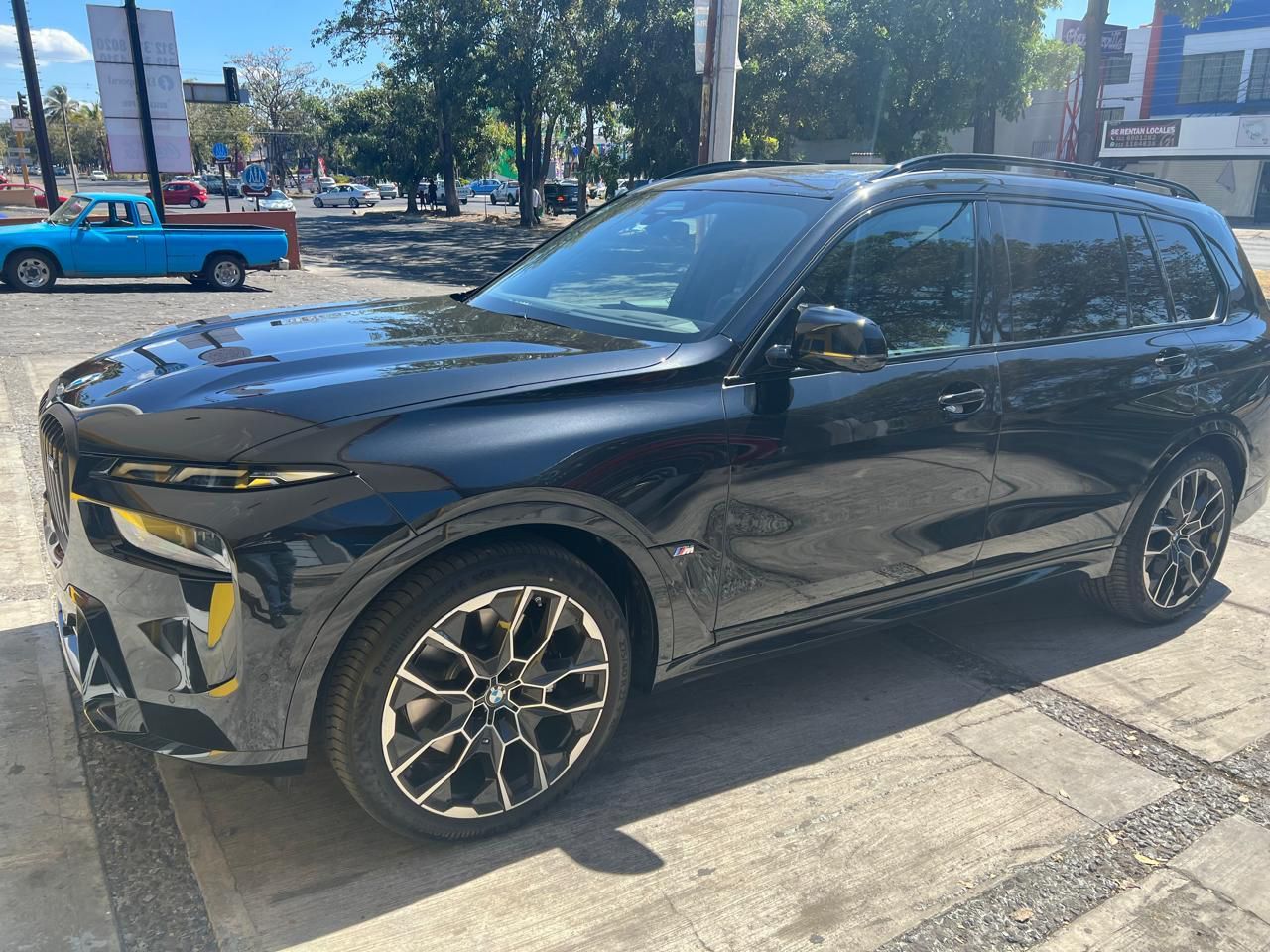 Una camioneta negra está estacionada en un estacionamiento al lado de un camión azul.
